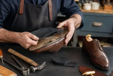 Sapateiro trocando solado de sapatos com ferramentas especializadas.